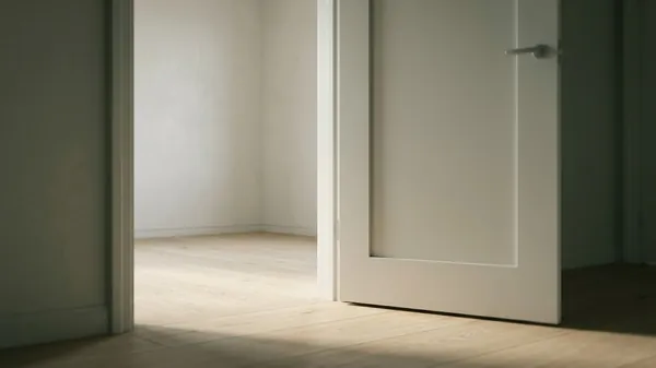 A white door standing open onto an empty sunlit room with a pale wood floor, illustrating how to fire someone with a clear and respectful exit