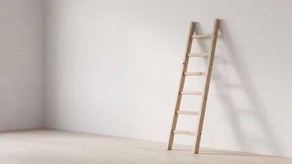 A pale wood ladder with six rungs leaning against a white wall in an empty sunlit room, illustrating a leadership development program built step by step in a 20 to 200 person company