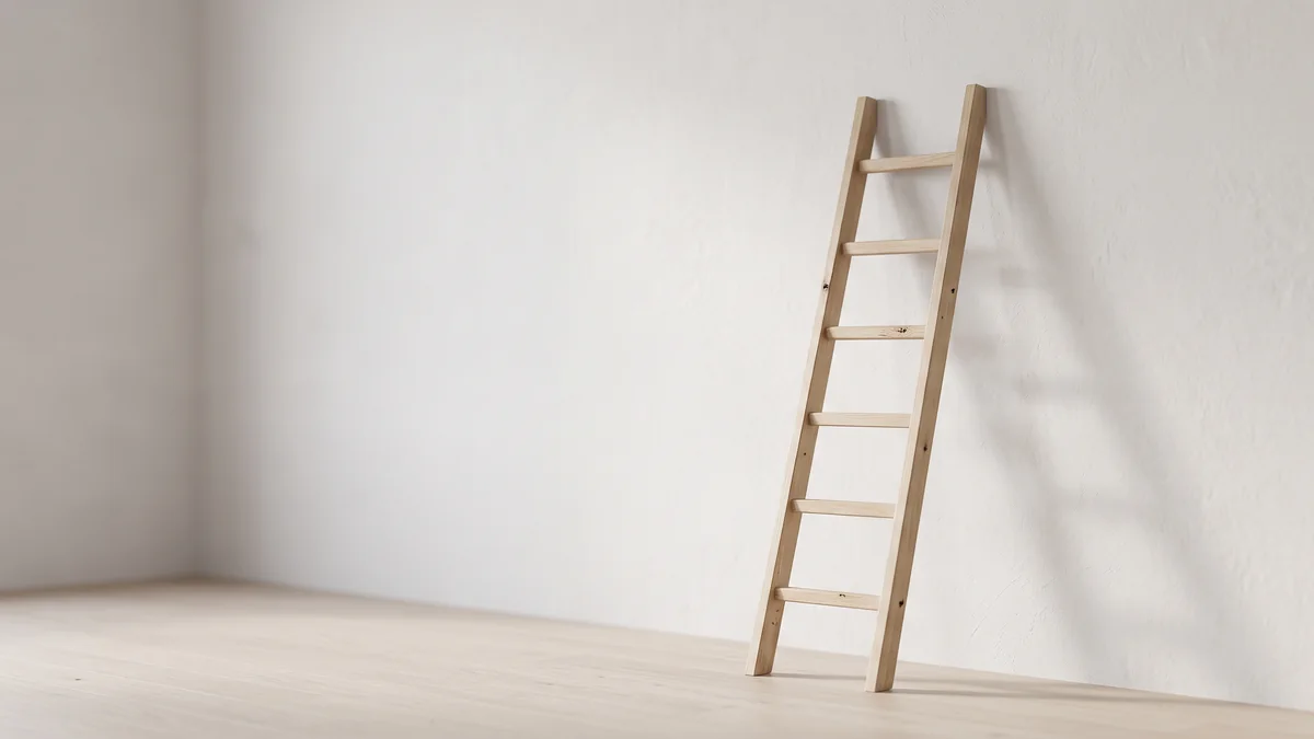 A pale wood ladder with six rungs leaning against a white wall in an empty sunlit room, illustrating a leadership development program built step by step in a 20 to 200 person company